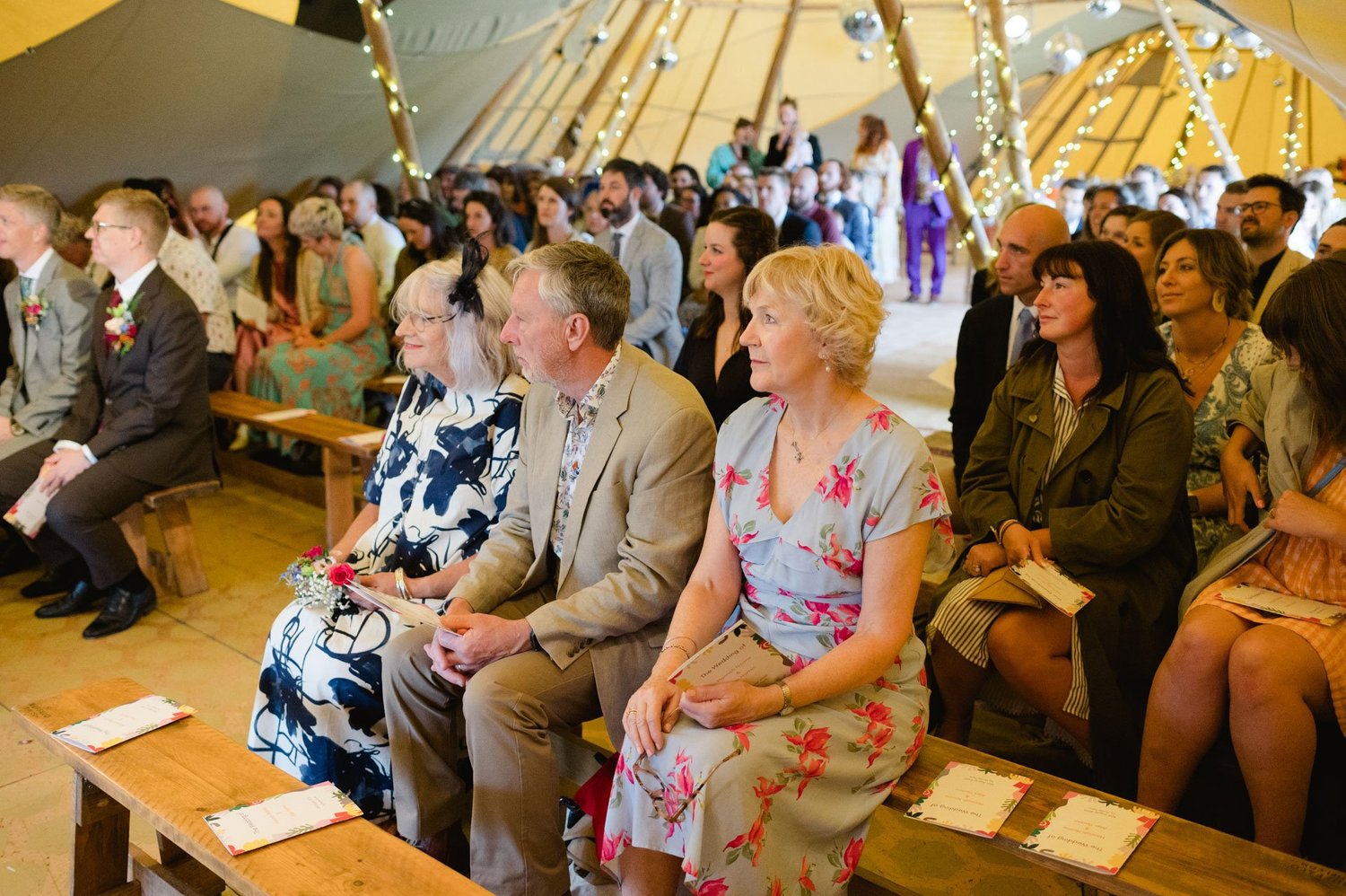 Wedding guests seated on benches for the tipi ceremony