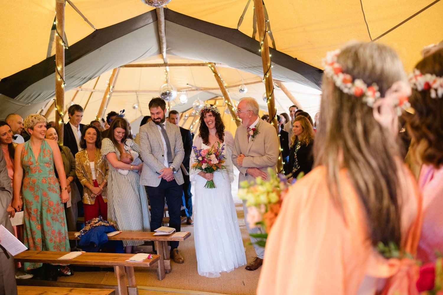 Hannah walking down the tipi aisle with guests watching