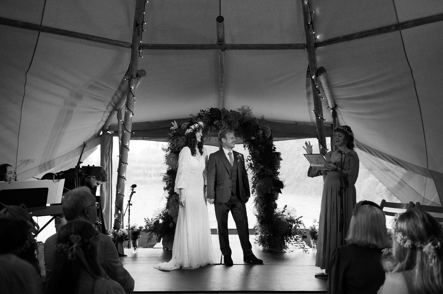 Hannah and Alex exchanging vows beneath the tipi poles