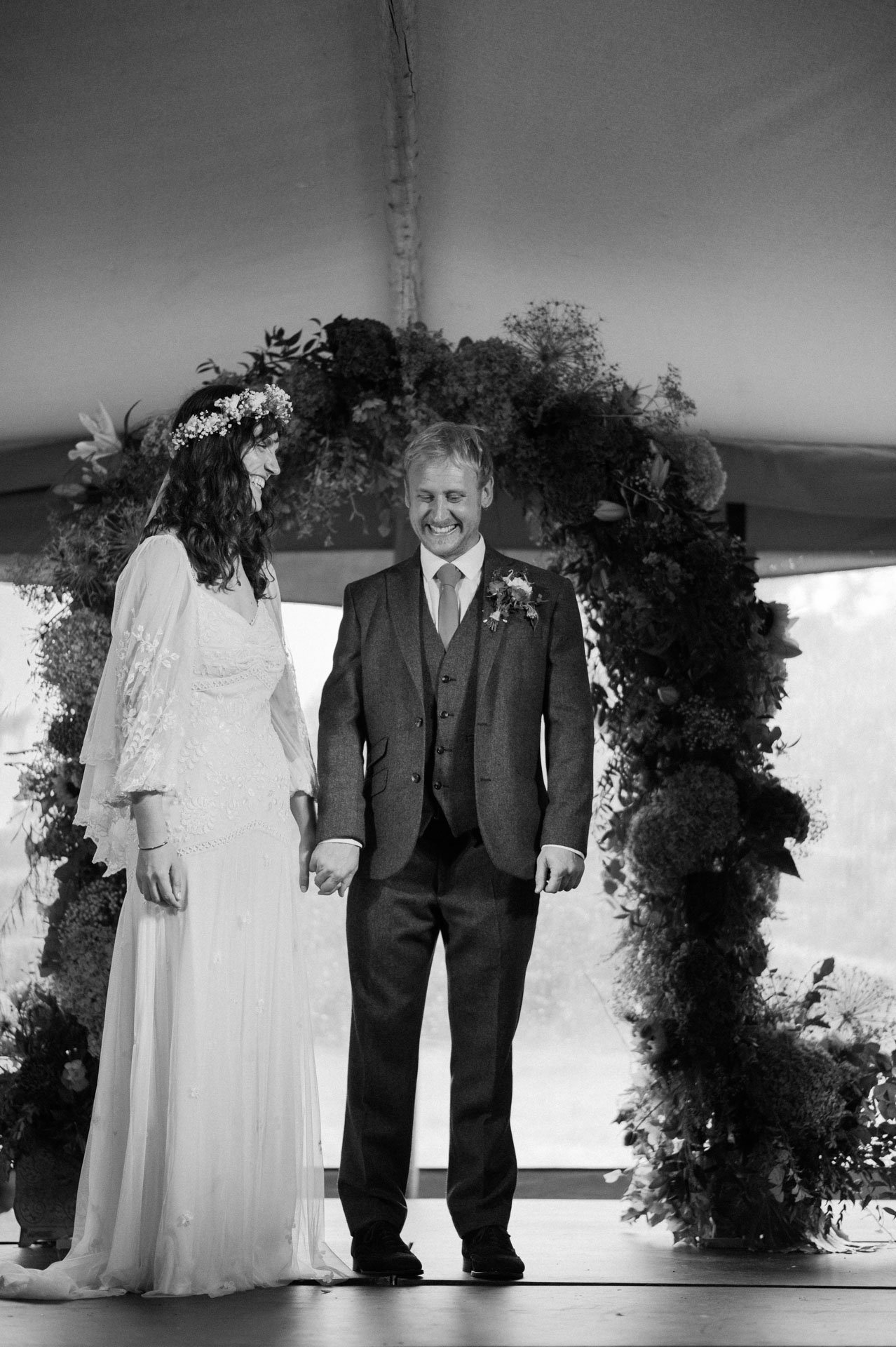 Hannah and Alex posing beneath the floral arch
