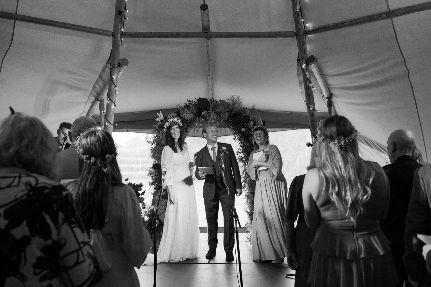 Hannah and Alex standing with their celebrant in the tipi