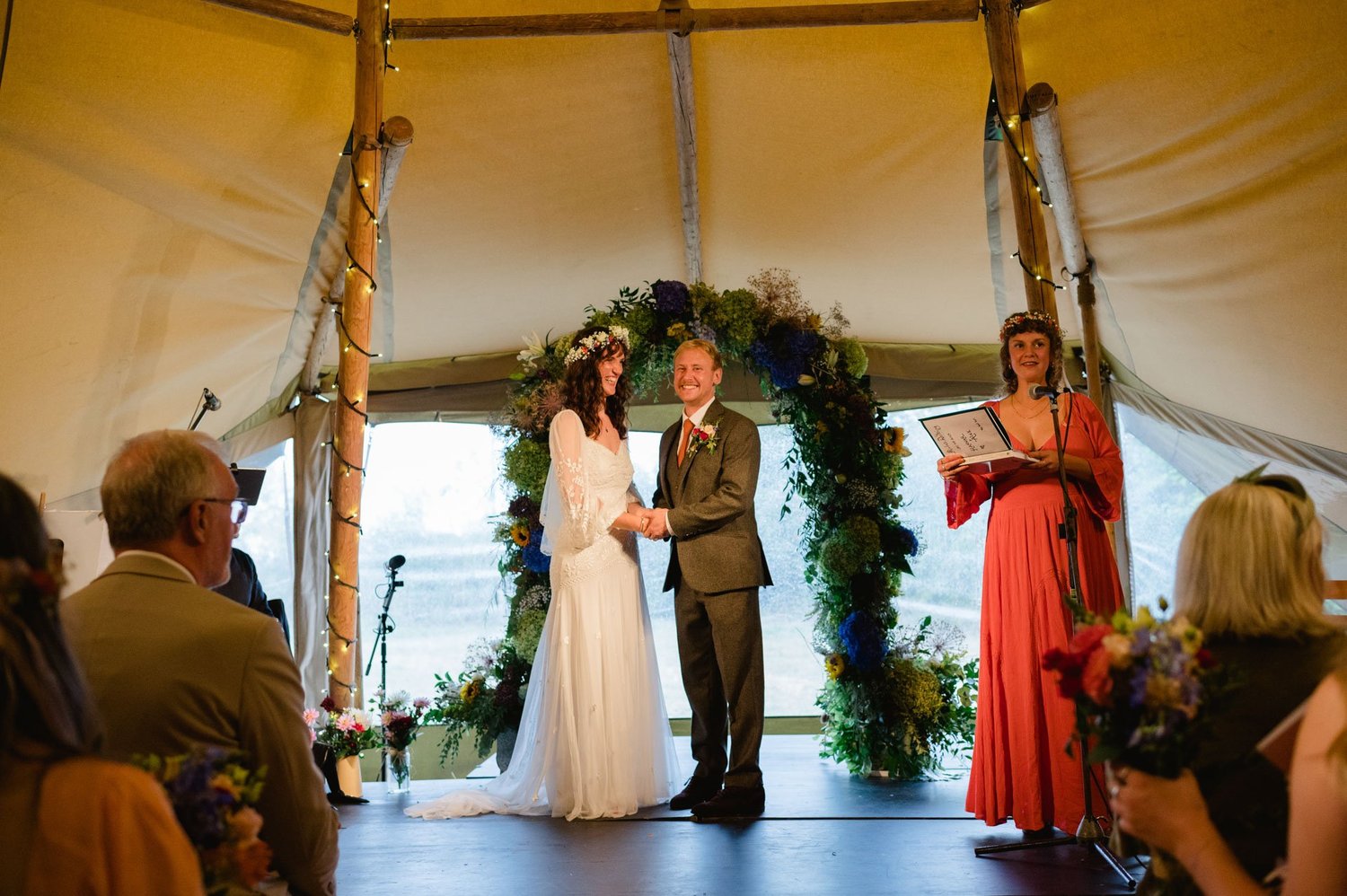 Hannah and Alex exchanging vows beneath the floral arch