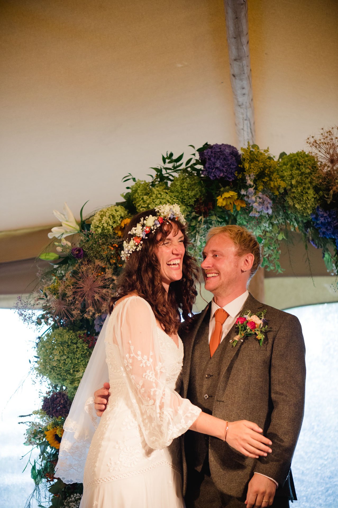 Hannah and Alex smiling together under the floral arch
