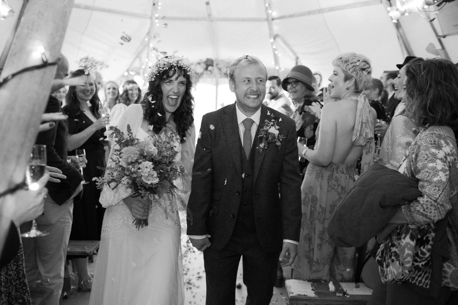 Hannah and Alex smiling as guests throw confetti in the tipi