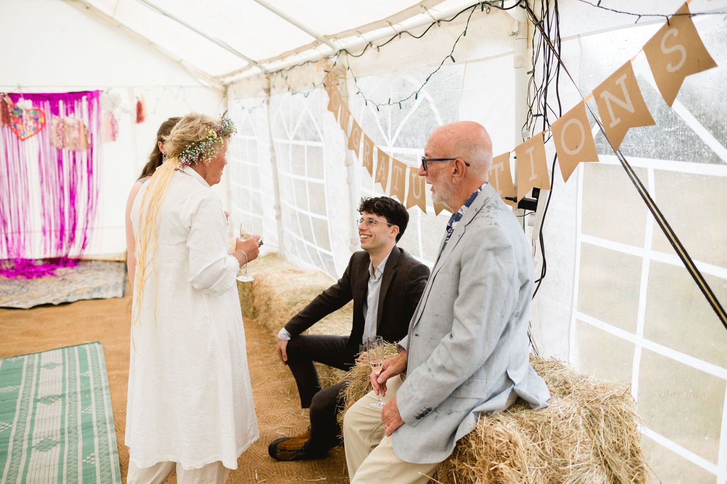A family member speaking to seated guests on hay bales