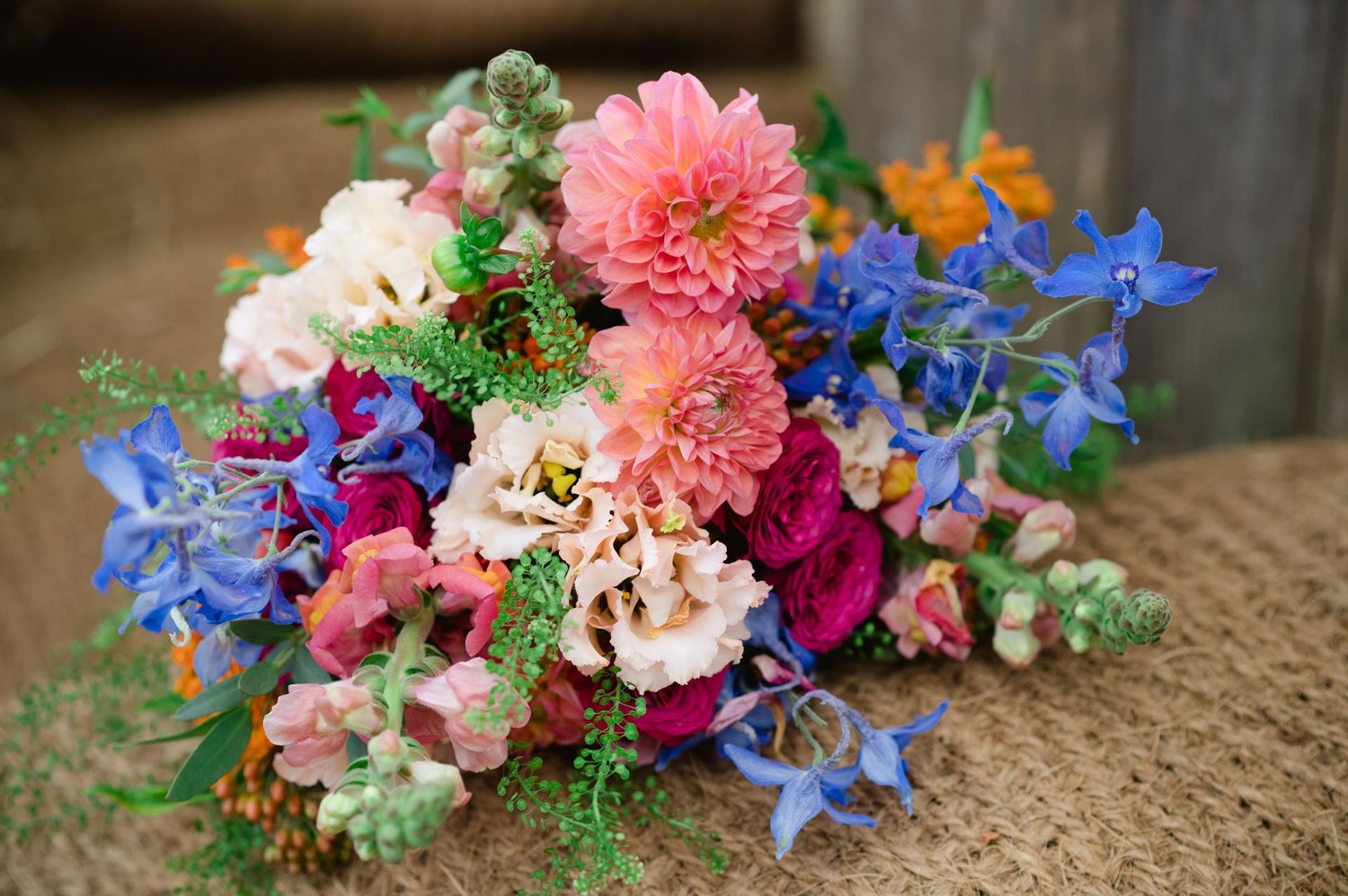 Bright wedding bouquet with dahlias and blue flowers on a hay bale