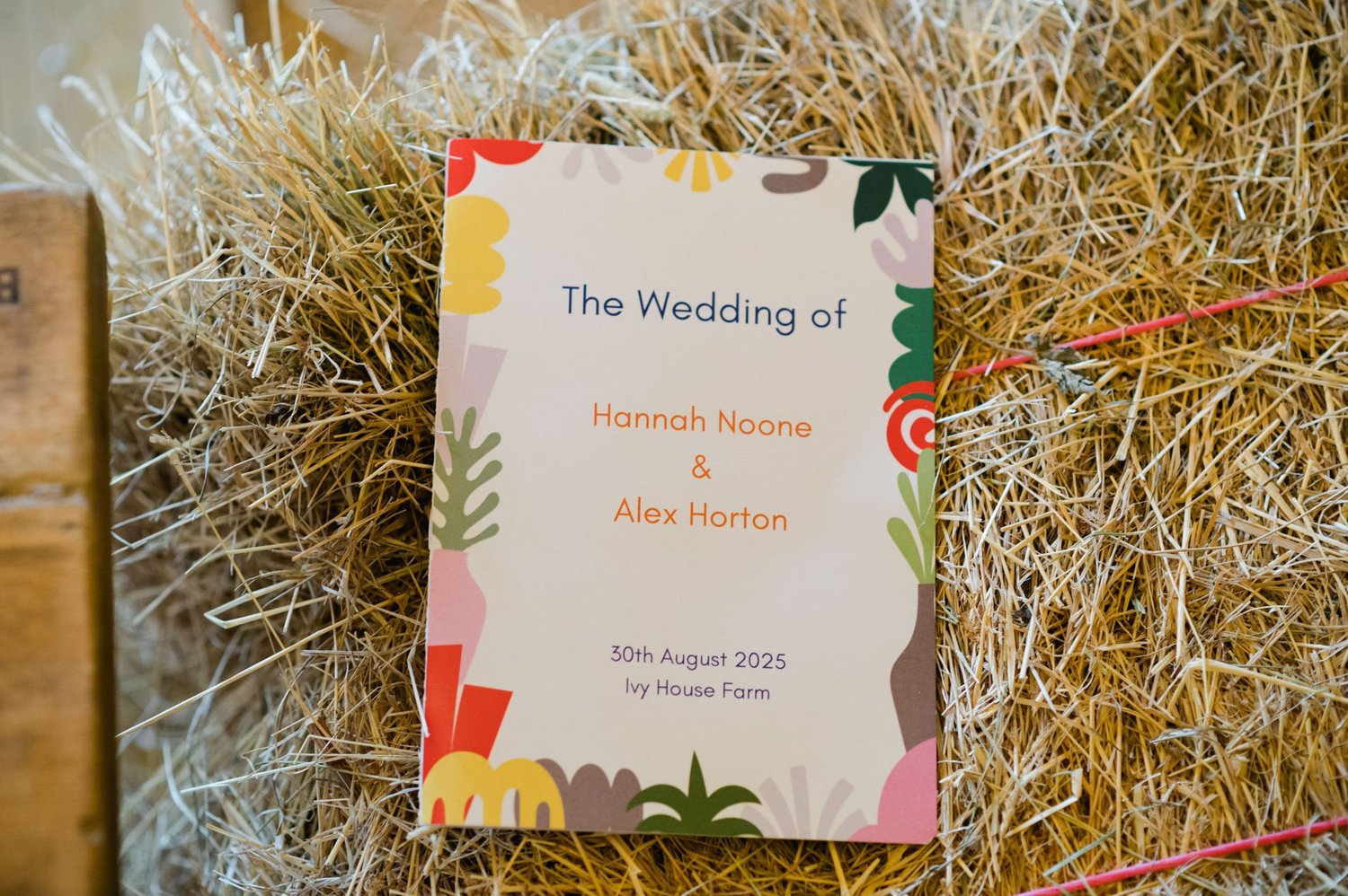 Colourful wedding programme for Hannah and Alex on a hay bale