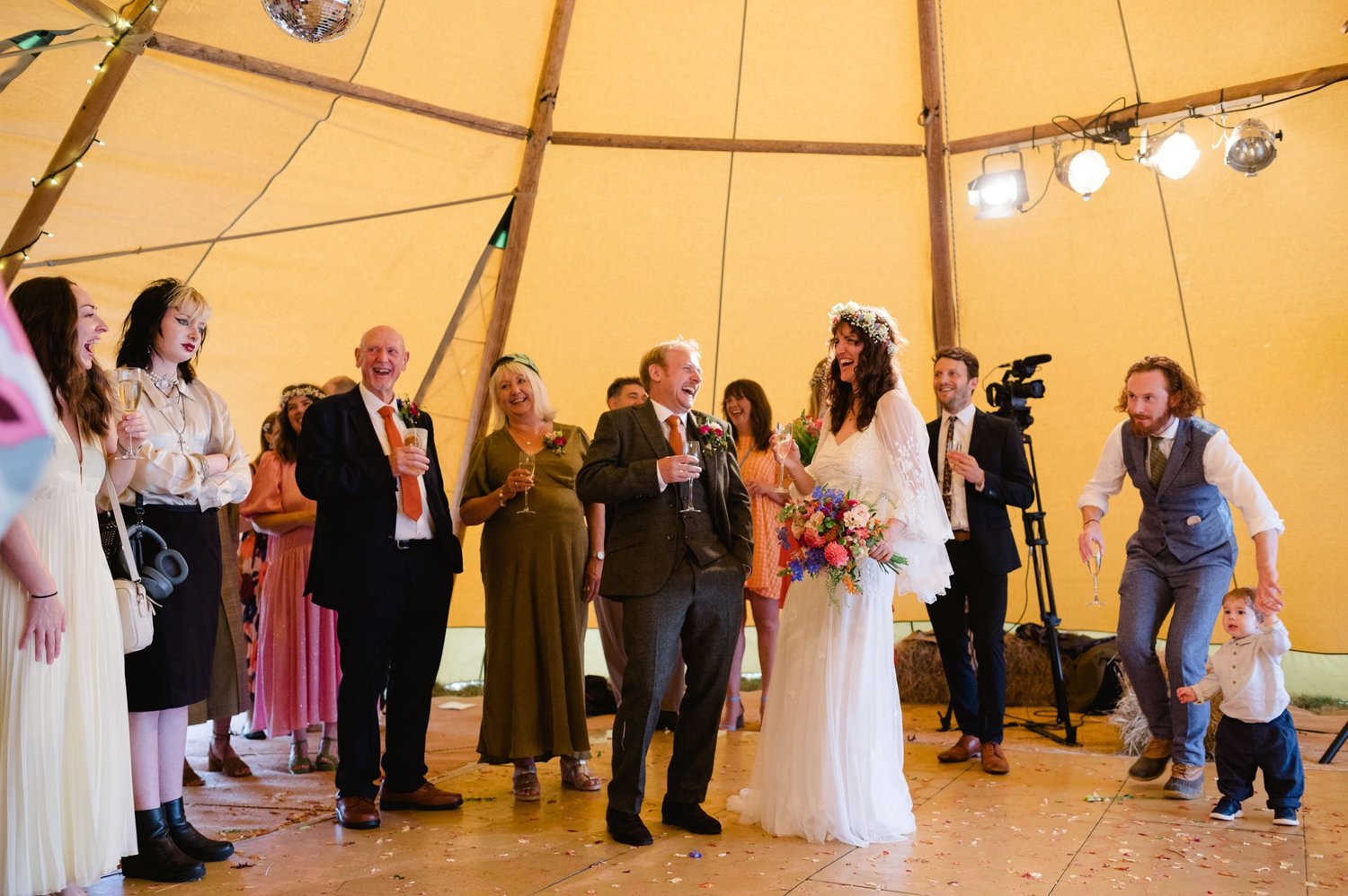 Family members raising drinks around Hannah and Alex in the tipi