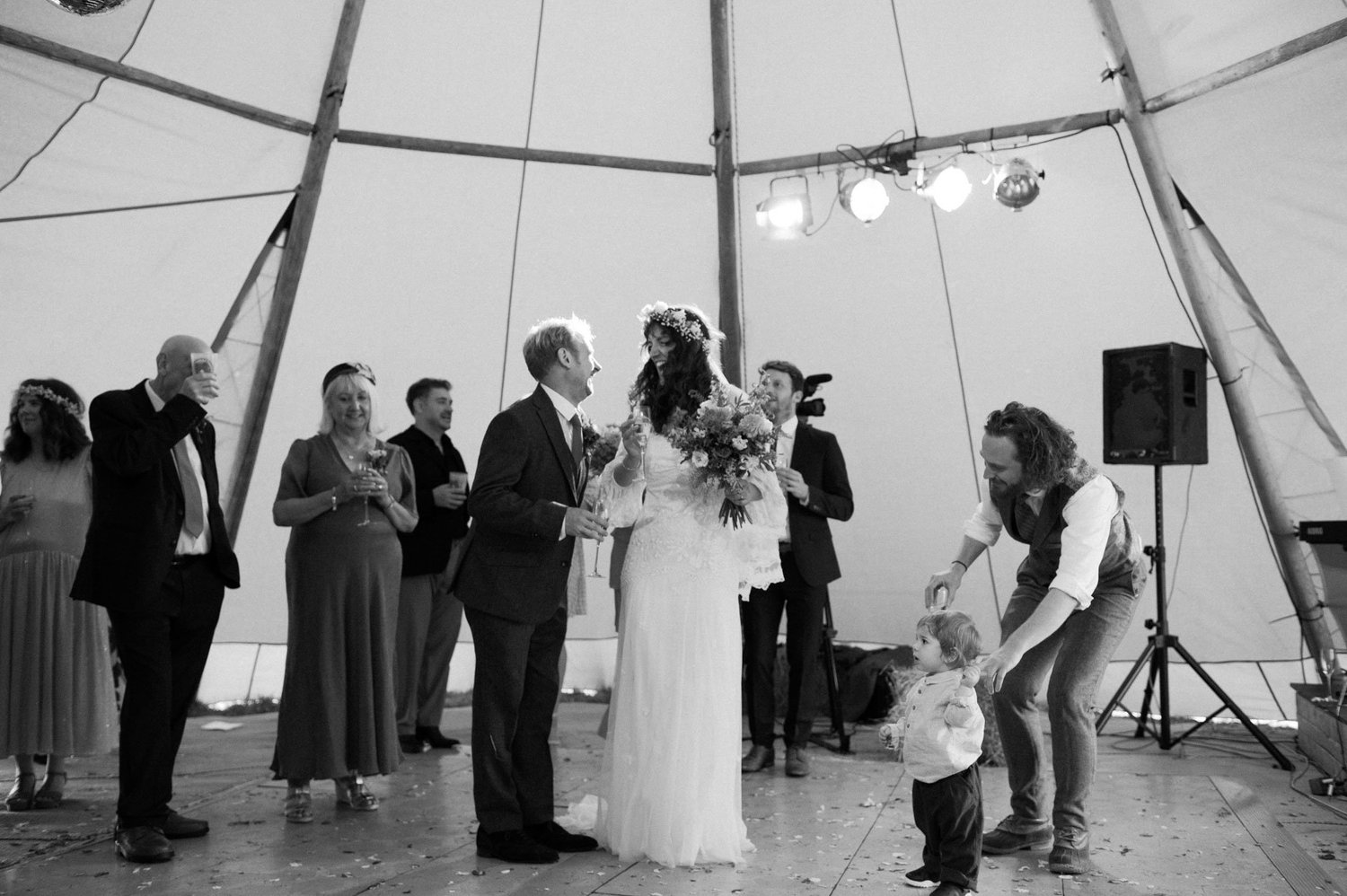 A child walking past as guests toast Hannah and Alex