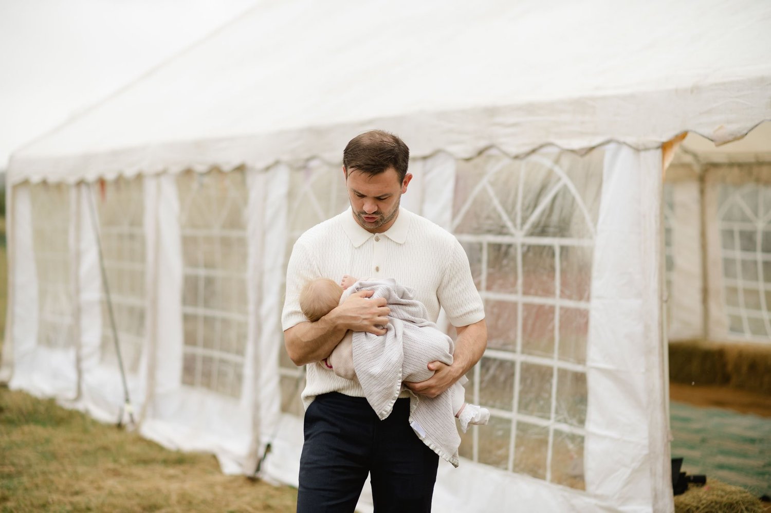 A guest holding a baby outside the white reception marquee