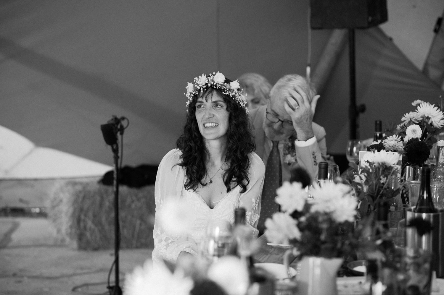 Hannah smiling during speeches at the flower-filled top table