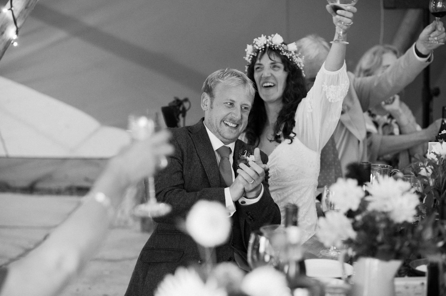 Hannah and Alex raising glasses with guests in the tipi