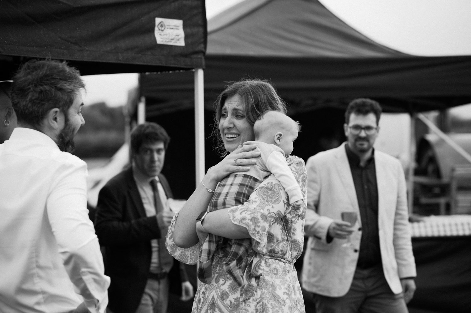 A guest cuddling a baby during the outdoor reception