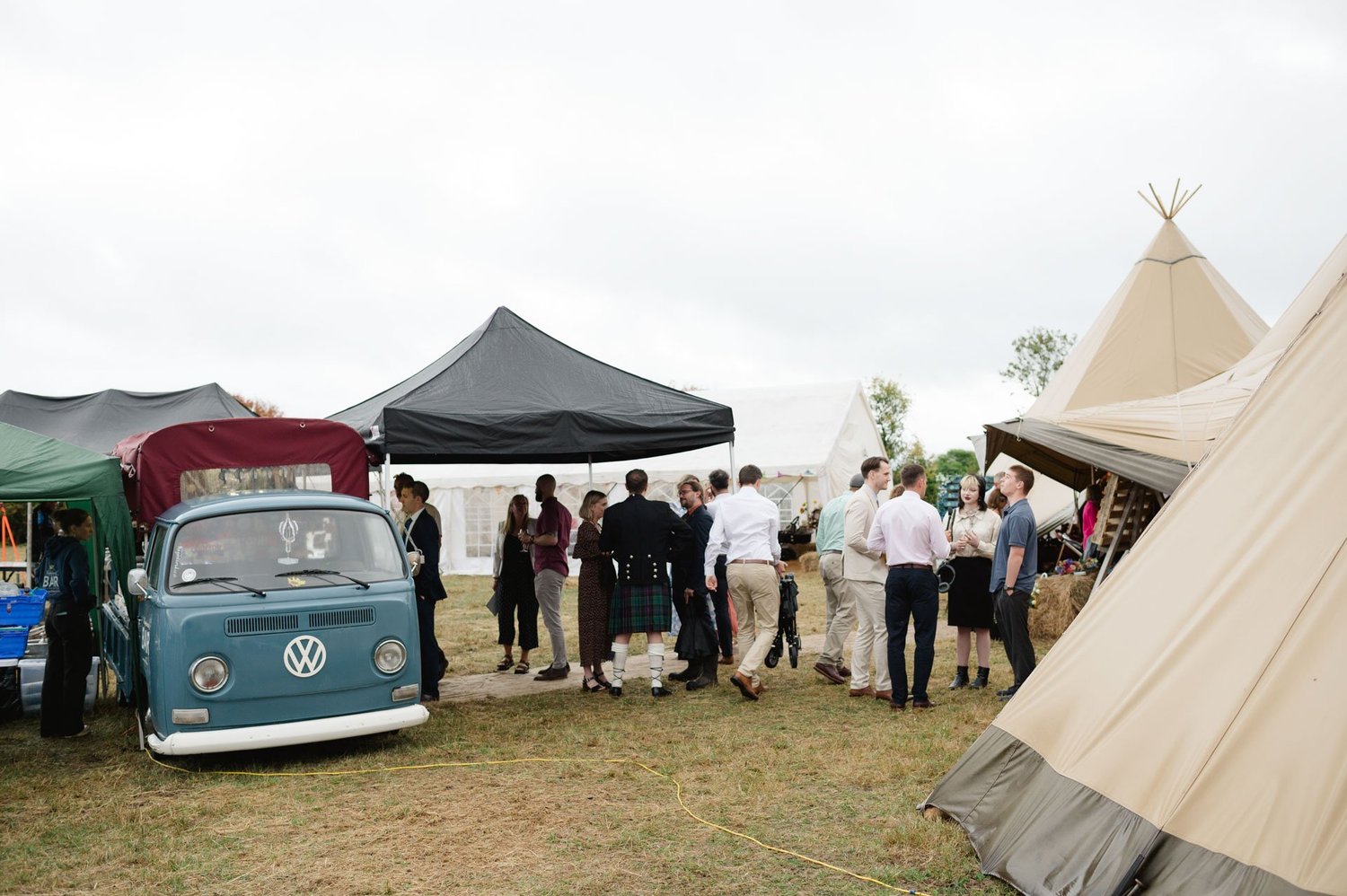 Guests gathered near the vintage VW bar and tipi entrance