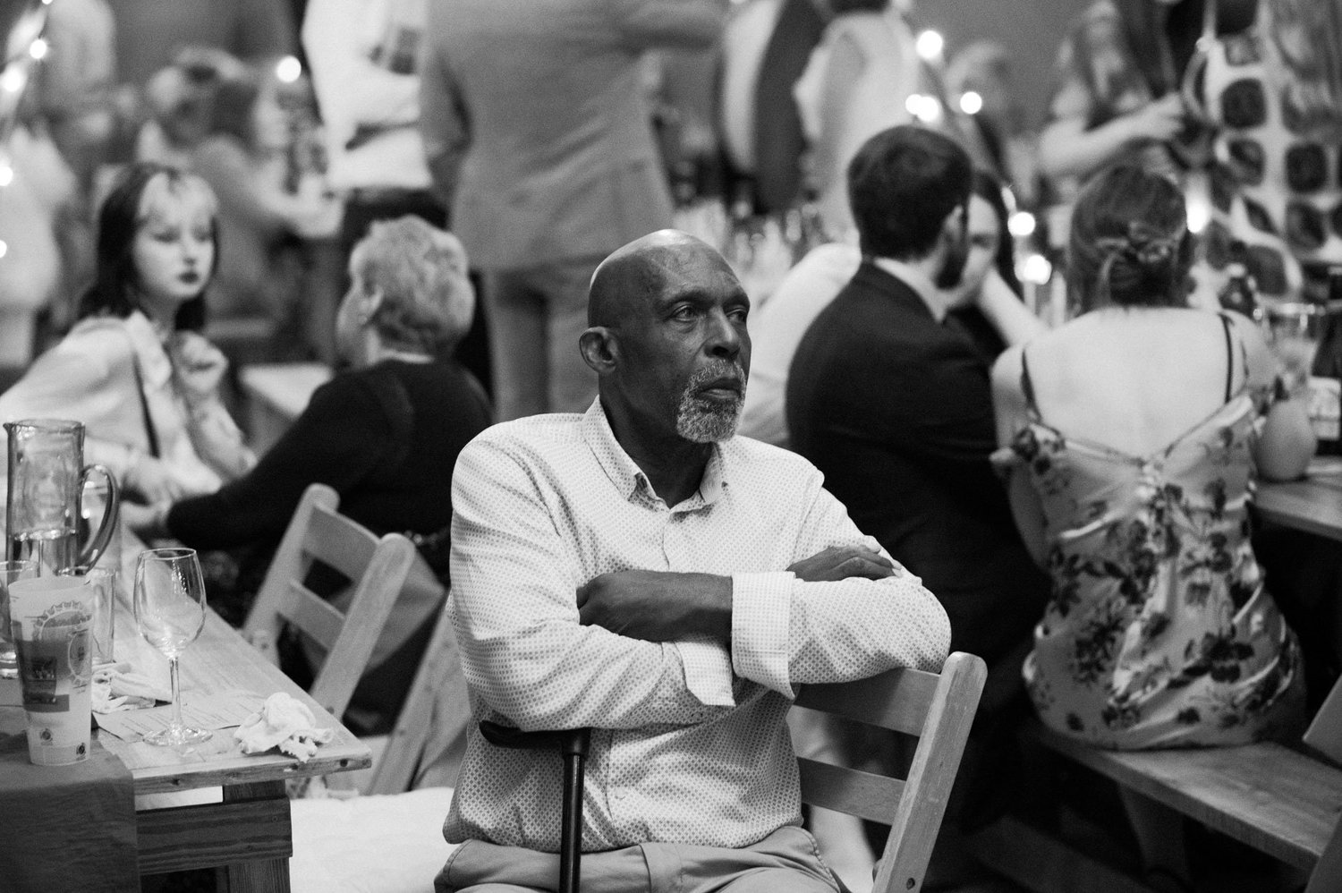 A guest watching the busy tipi reception in black and white