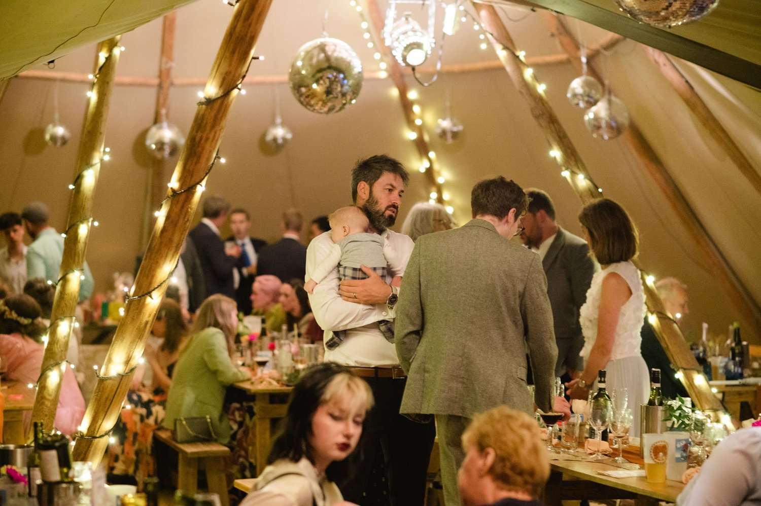 Guests seated under string lights at the tipi reception